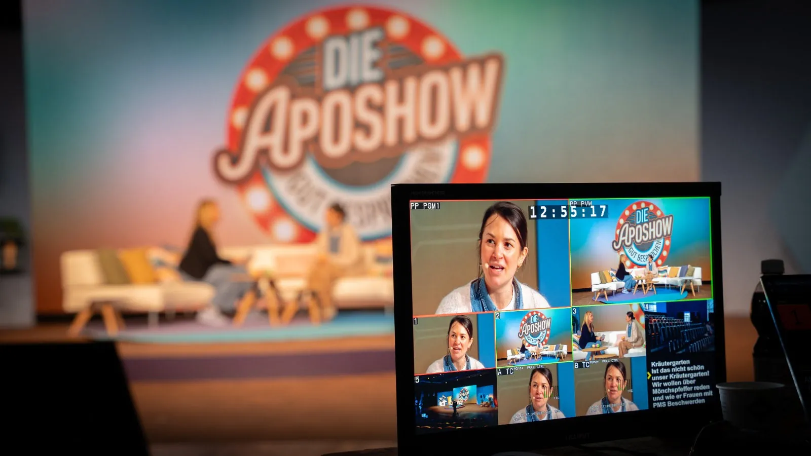 Multiviewer mit Programm- und Vorschaubild, Timecode und den Kamerasignalen, dahinter unscharf die ApoShow-Bühne mit Sofa und Gästen