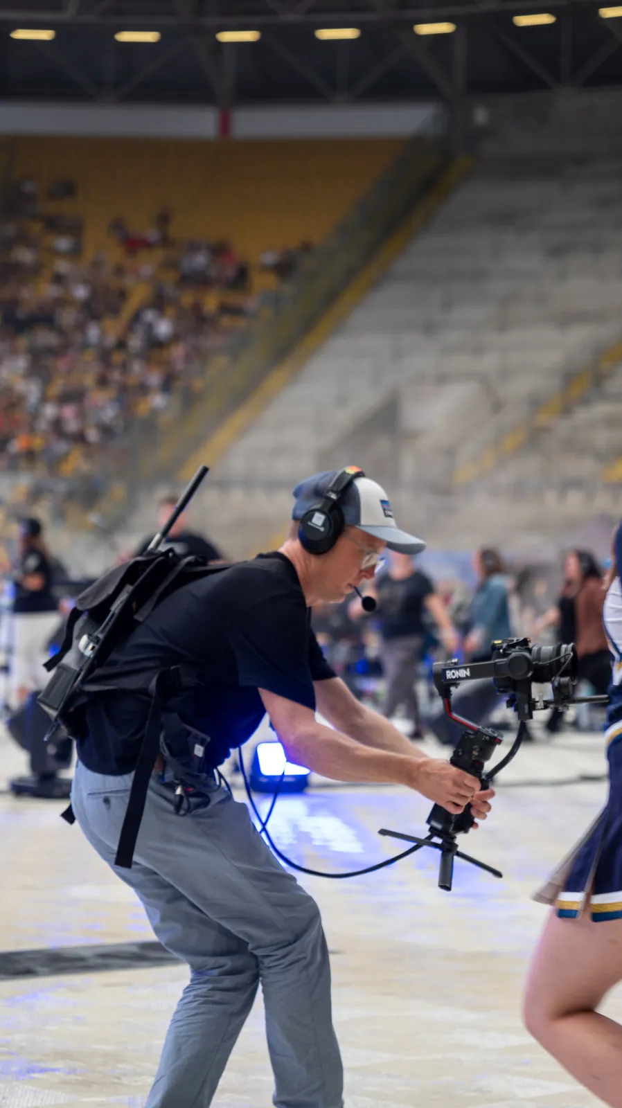 Kameramann mit Gimbal-Kamera und Headset zwischen den Zuschauerreihen